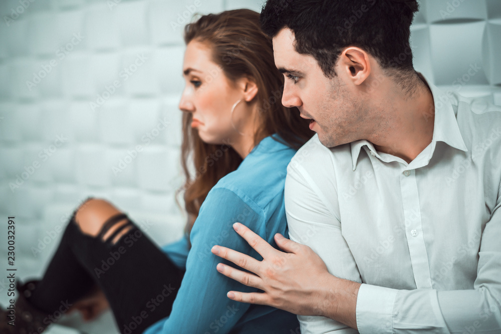 Cinematic tone of young handsome man trying to reconcile with his beautiful girlfriend after have an argument on sofa. Cinematic tone of young handsome man trying to reconcile with his beautiful girlfriend after have an argument on sofa.