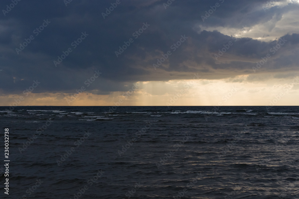 Rain clouds over Baltic sea near shoreline just before sunset, selective focus