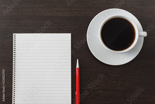 Notebook with pen and cup of coffee on brown wooden table