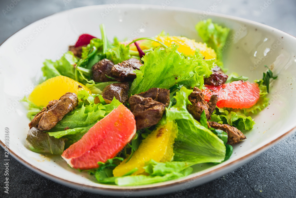 Tasty salad with citrus, lettuce and grilled chicken liver in a plate. Close up view Tasty salad with citrus, lettuce and grilled chicken liver in a plate. Close up view