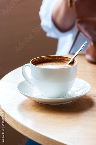 Close up of cup of coffee on a working table  woman holding her