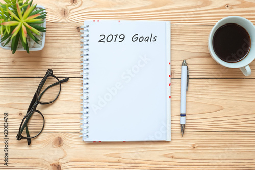 2019 Goals with notebook, black coffee cup, pen and glasses on table, Top view and copy space. New Year New Start, Resolution, Solution, Strategy and Mission concept