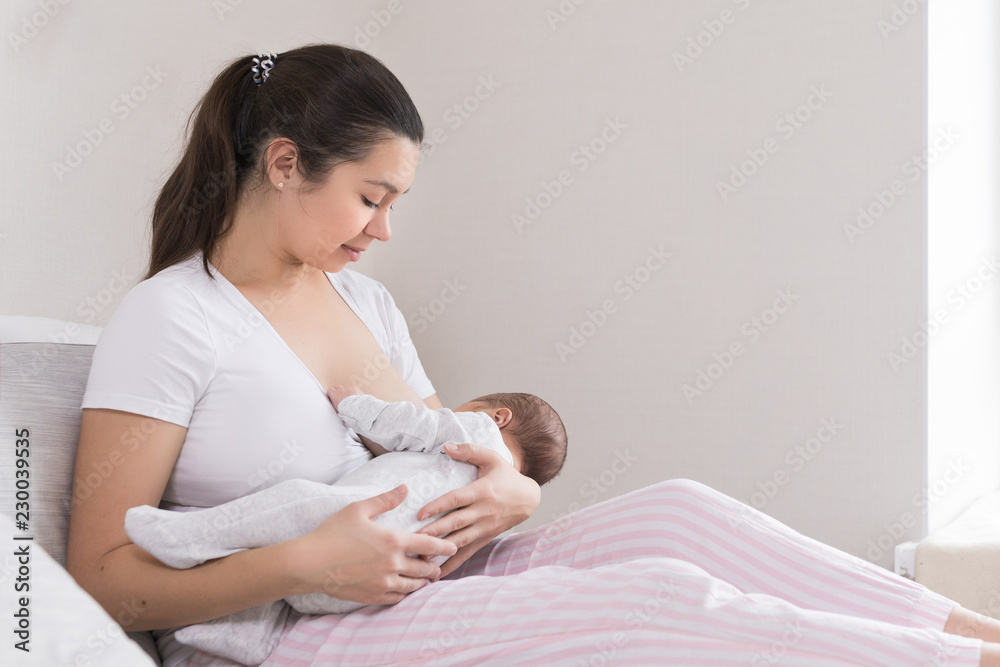 Young mother breast feeding, nursing and hugging baby. Mom