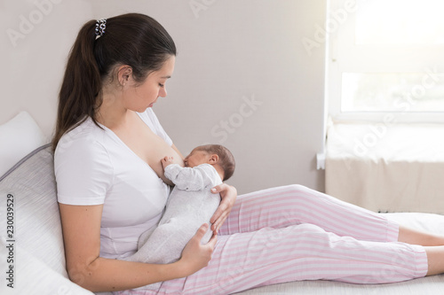 Young mother breastfeeding her newborn baby son. Happy mom hugging her babyboy. Breast feeding and lactation infant concept.