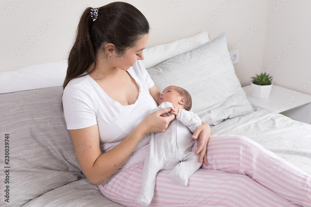Young happy calm mother and newborn baby resting in bed together. Mom and infant kissing and hugging. Maternity, parenthood, motherhood concept. Young happy calm mother and newborn baby resting in bed together. Mom and infant kissing and hugging. Maternity, parenthood, motherhood concept.