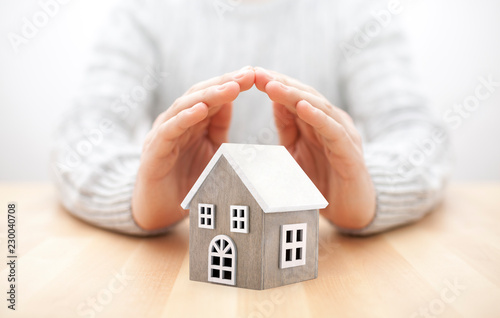 Small wooden house covered by hands 