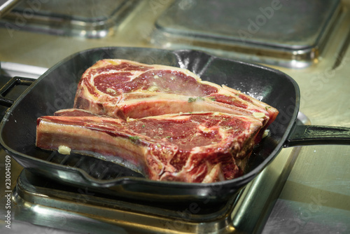 Raw fresh meat T-bone steak on grill iron pan