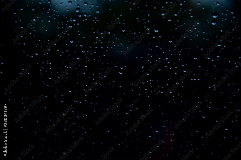 Obraz premium Drop water in glass on dark or black background