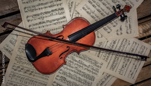 violin and bow on music sheet of paper