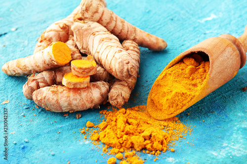 Turmeric powder and fresh turmeric on grey background photo