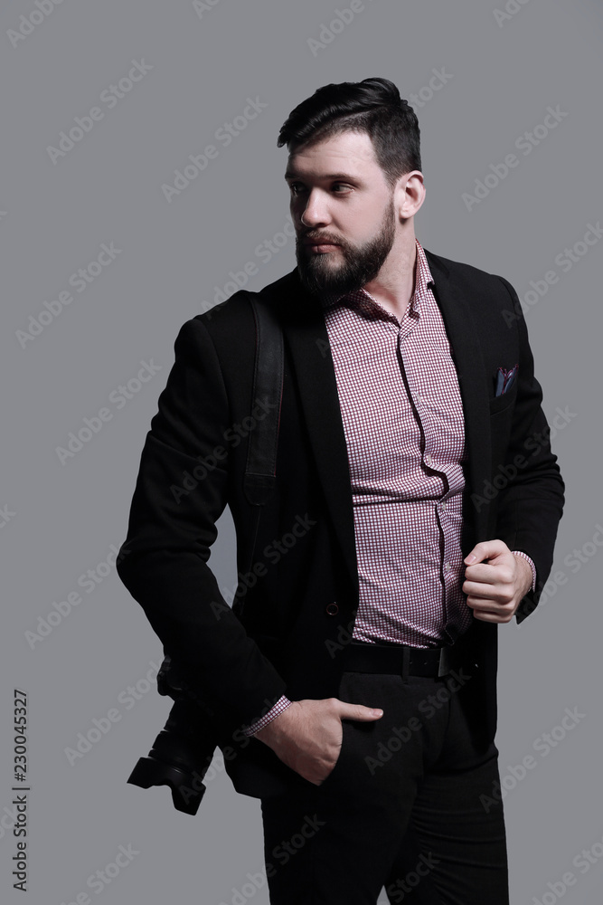 Fototapeta premium fashion photographer with a camera looking to the side.isolated on grey background