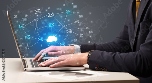 Businessman hand sending a bunch of messages on laptop with cloud computing concept
