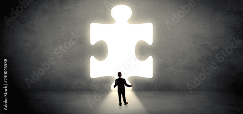 Businessman  standing and looking to a big puzzle piece
