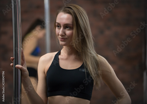 Young woman in sport clothes staying next by the pole