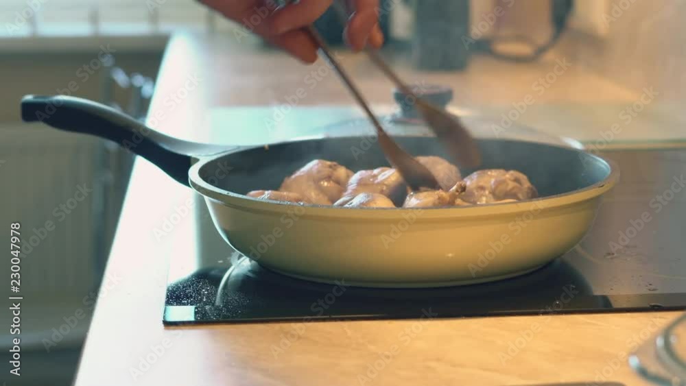 Father in a plaid shirt is cooking fresh chicken drumsticks for his children for dinner in the domestic home kitchen Father in a plaid shirt is cooking fresh chicken drumsticks for his children for dinner in the domestic home kitchen