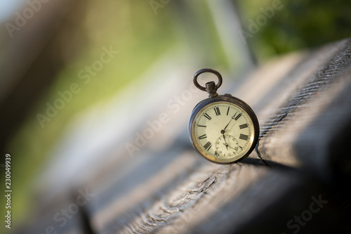 Retro Taschenuhr auf Holzbank, Symbol für Zeit photo