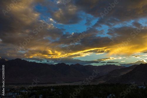 sunset from behind the mountains illuminates the beautiful colorful sky above the city