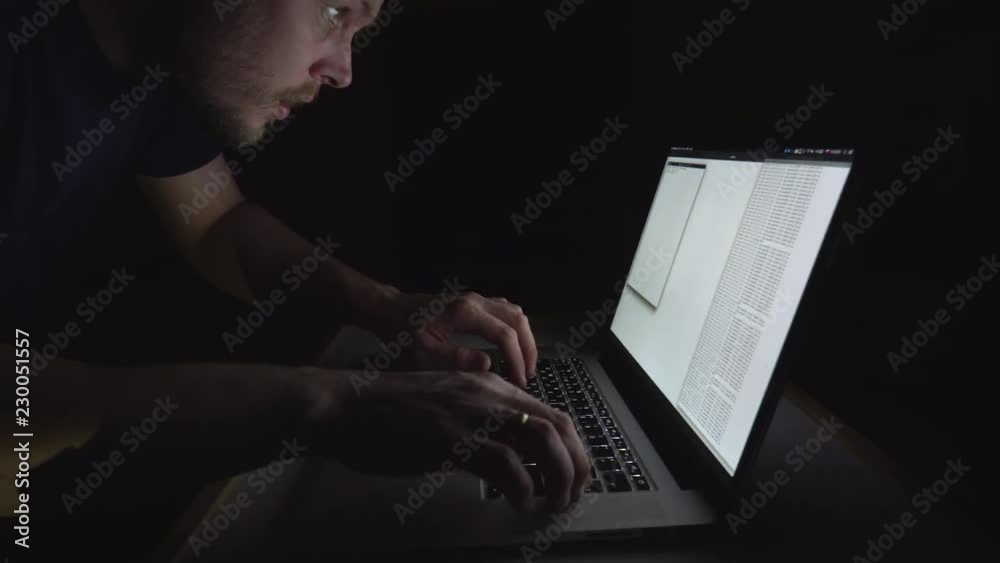 Federal crime. Male, allegedly criminal hacker, is trying to hack government server at night. Laptop with Russian and English layout.