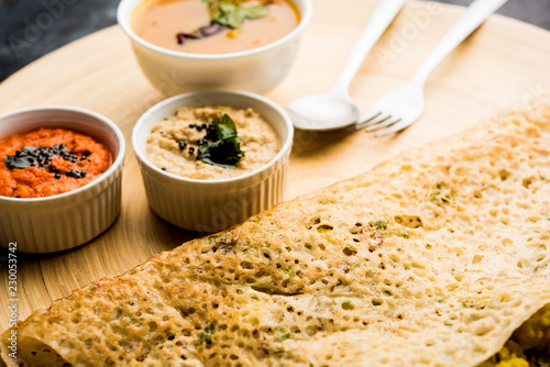 Onion rava masala dosa is a South Indian instant breakfast served with chutney and sambar over moody background. selective focus