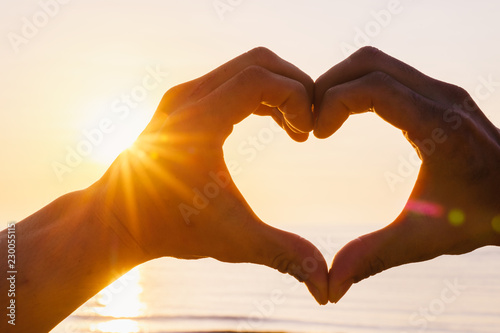 Hands as heart shape with beautiful sky in warm color twilight sunset and sea background  love and romantic concept.