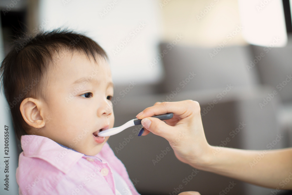 Mother feeding baby with spoon indoors Mother feeding baby with spoon indoors