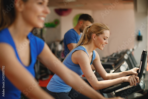 Young woman and man warming up on bikes in the gym