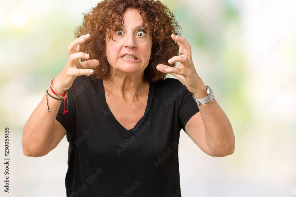Beautiful middle ager senior woman over isolated background Shouting frustrated with rage, hands trying to strangle, yelling mad