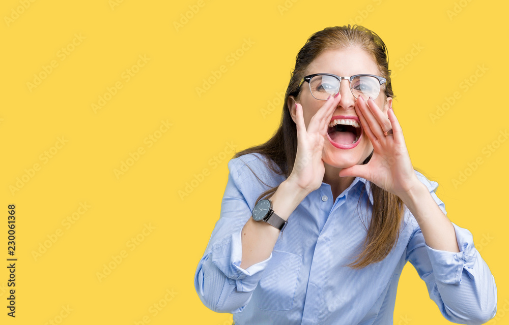 Beautiful middle age mature business woman wearing glasses over isolated background Shouting angry out loud with hands over mouth Beautiful middle age mature business woman wearing glasses over isolated background Shouting angry out loud with hands over mouth