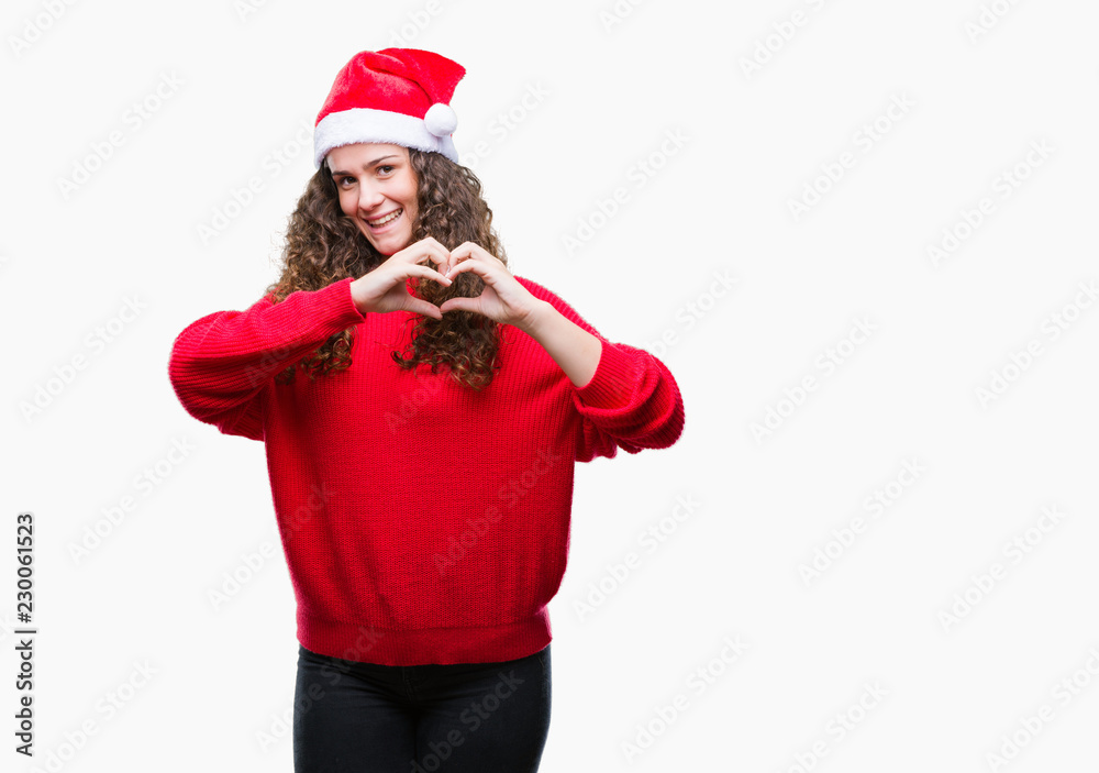 Young brunette girl wearing christmas hat over isolated background smiling in love showing heart symbol and shape with hands. Romantic concept. Young brunette girl wearing christmas hat over isolated background smiling in love showing heart symbol and shape with hands. Romantic concept.