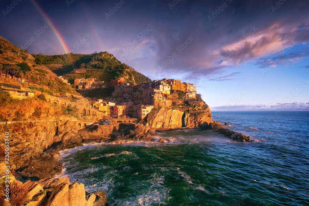Manarola Village, Cinque Terre Coast, Liguria, Italy. The fishing village on the sea coast is a UNESCO World Heritage site. Landscape with a rainbow.