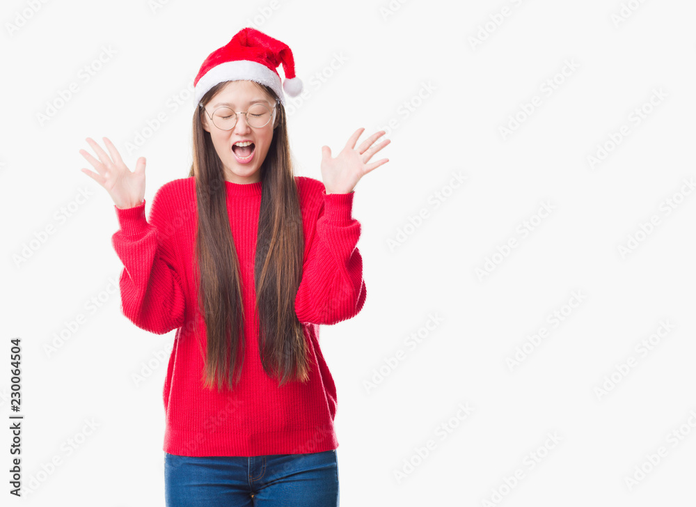 Young Chinese woman over isolated background wearing christmas hat celebrating mad and crazy for success with arms raised and closed eyes screaming excited. Winner concept Young Chinese woman over isolated background wearing christmas hat celebrating mad and crazy for success with arms raised and closed eyes screaming excited. Winner concept