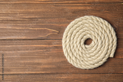 Hemp rope on wooden background, top view. Space for text