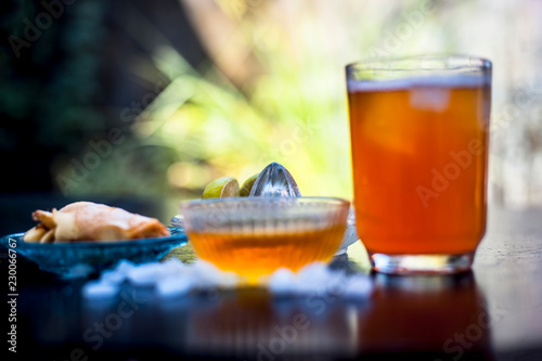 Close up of popular ginger dirnk i.e. Ginger zinger on wooden surafce in a transparent glass  with entire raw ingredients that are sugar,honey,ginger,club soda, and lemon juice.Top shot. photo