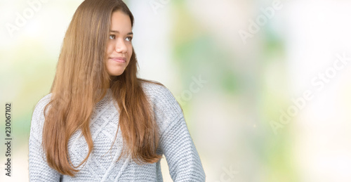 Young beautiful brunette woman wearing sweater over isolated background looking away to side with smile on face, natural expression. Laughing confident.