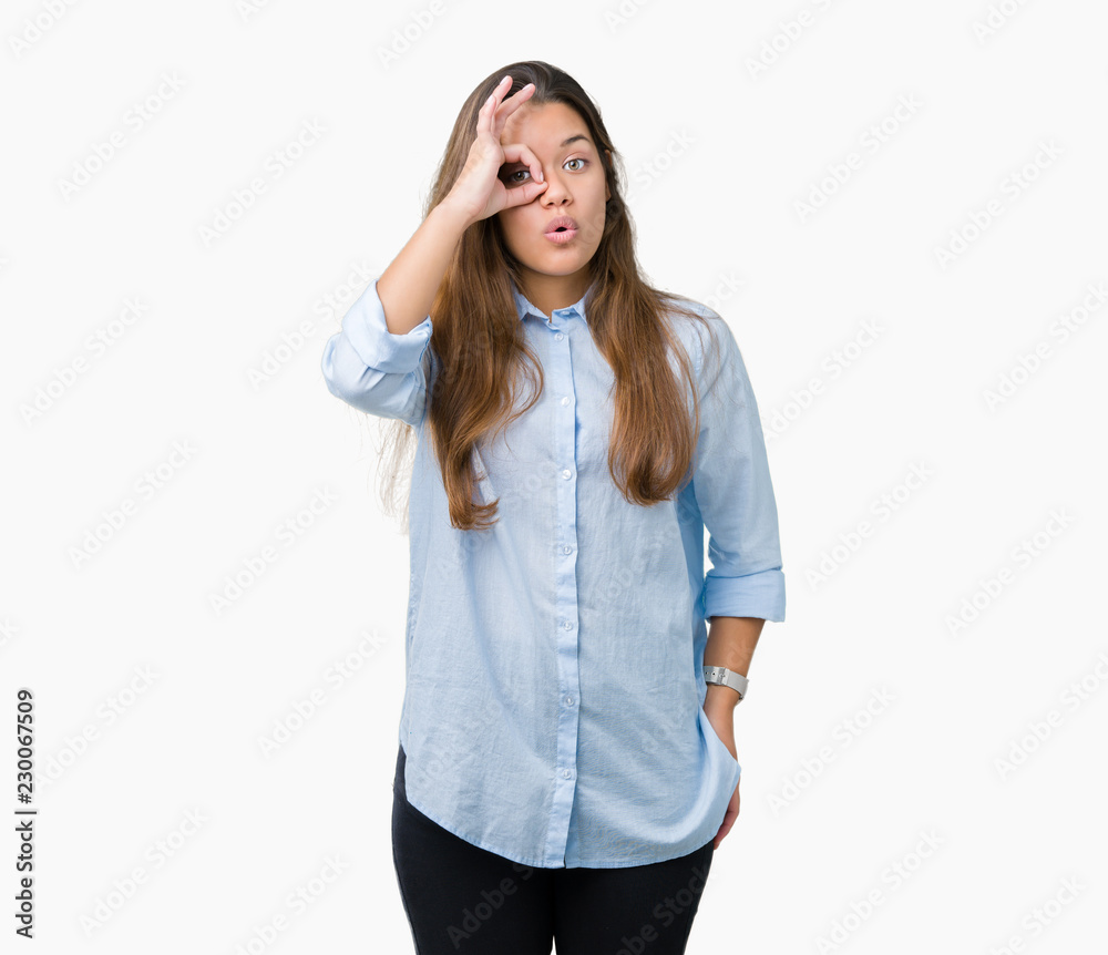 Young beautiful brunette business woman over isolated background doing ok gesture shocked with surprised face, eye looking through fingers. Unbelieving expression. Young beautiful brunette business woman over isolated background doing ok gesture shocked with surprised face, eye looking through fingers. Unbelieving expression.