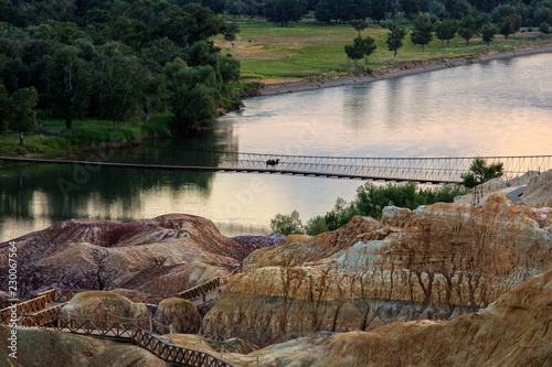 Camel Crossing a Bridge at Rainbow Beach, Five Colored Hills scenic area, an oasis in the desert near Burqin. Buerjin, Altay, Xinjiang Province, China. Colorful hills and the beautiful Irtysh River. photo