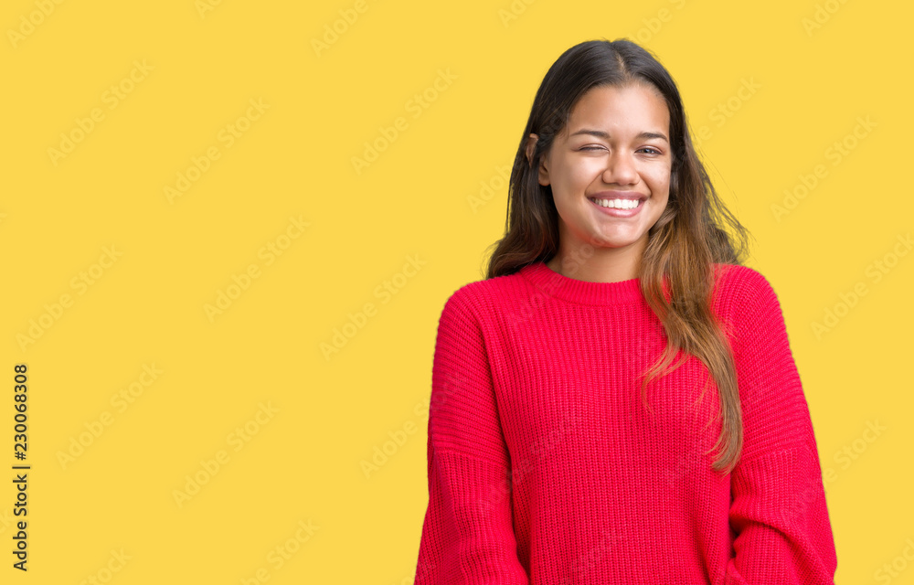 Fototapeta premium Young beautiful brunette woman wearing red winter sweater over isolated background winking looking at the camera with sexy expression, cheerful and happy face.