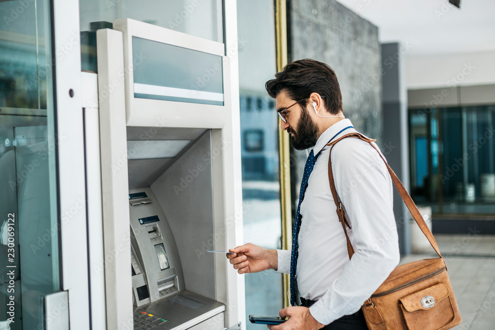 Businessman using card at an ATM Businessman using card at an ATM
