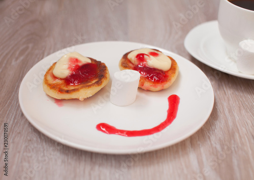Summer cottage cheese pancakes on white plates on a table with jam, closeup, Smiling. Smile for sweet breakfast with love