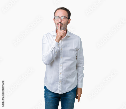 Handsome middle age elegant senior business man wearing glasses over isolated background asking to be quiet with finger on lips. Silence and secret concept. © Krakenimages.com