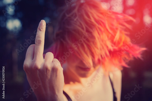 Fototapeta Naklejka Na Ścianę i Meble -  Woman showing middle finger gesture. Redhead woman showing a fuck you off sign