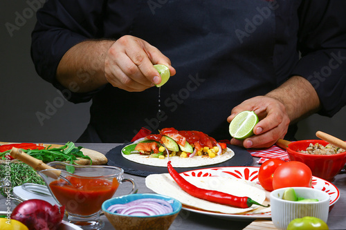 Lemon splash in chef hand under mexican burito. Cook preparing delicious mexican burito at kitchen. Tasty mexican cuisine