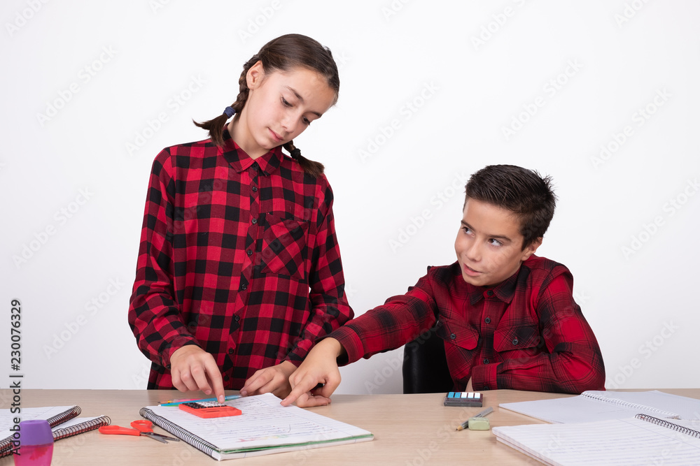 smiling child pointing the result of a problem to a girl in the notebook smiling child pointing the result of a problem to a girl in the notebook