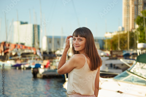 Portrait of a beautiful woman with freckles on the background of the sea and beautiful yachts © evafesenuk
