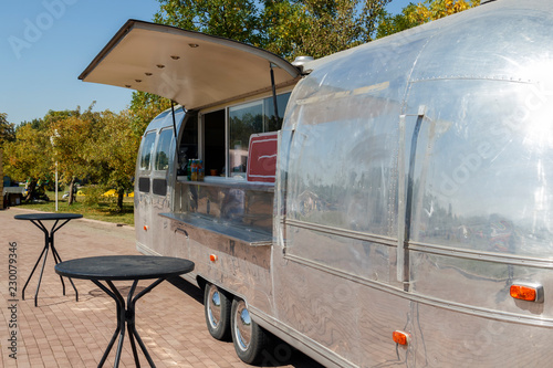 Metal trailer for selling food and tables for visitors stand on the street waiting for buyers. Copy space