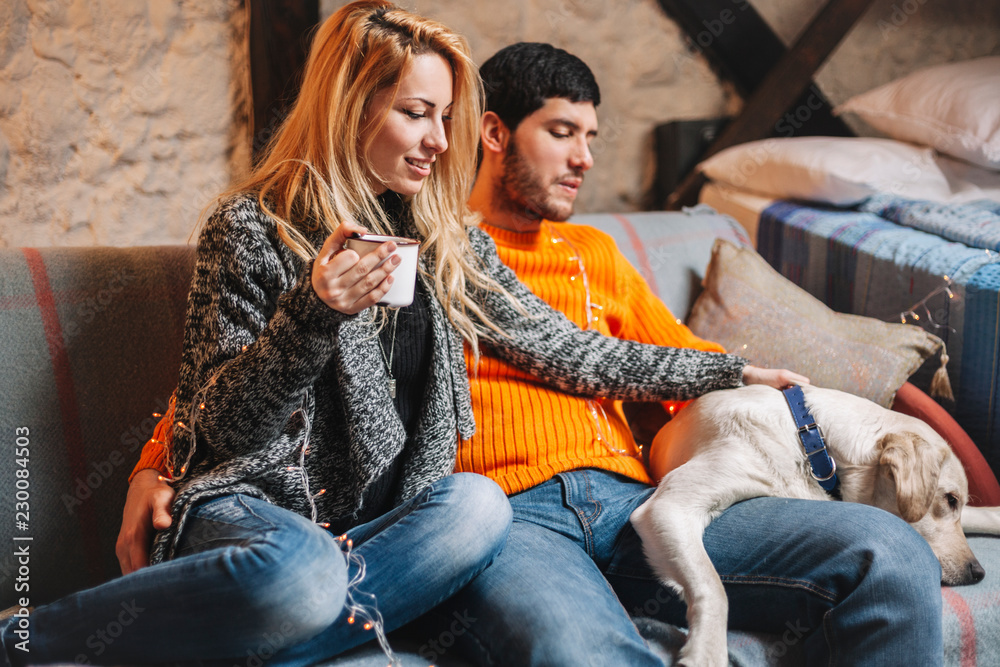 Loving couple relaxing at home and cuddling dog Loving couple relaxing at home and cuddling dog
