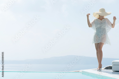attractive girl in tunic and wide-brimmed hat posing near the pool. © bigguns