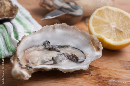 closeup of oysters and lemon on wooden cutting board