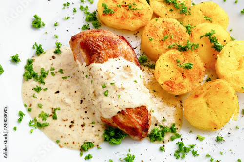 chicken breast under sour cream mustard sauce garnished with potato and sprinkled with parsley