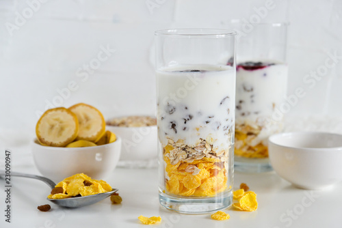Breakfast in glass Cup: homemade granola, banana, fresh berries, yogurt on white background. The concept of healthy eating, high-carbon Breakfast.